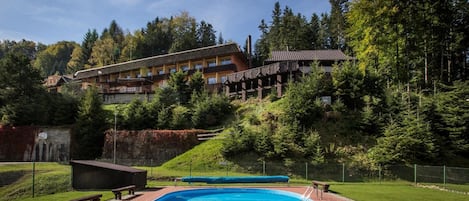 Un hotel con piscina, rodeado de árboles y un paisaje montañoso.