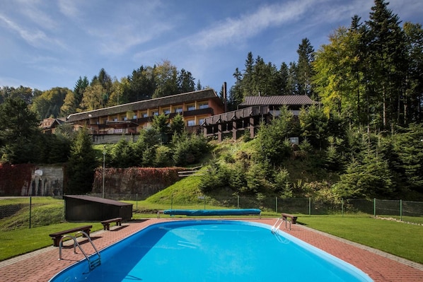Un hotel con piscina, rodeado de árboles y un paisaje montañoso.