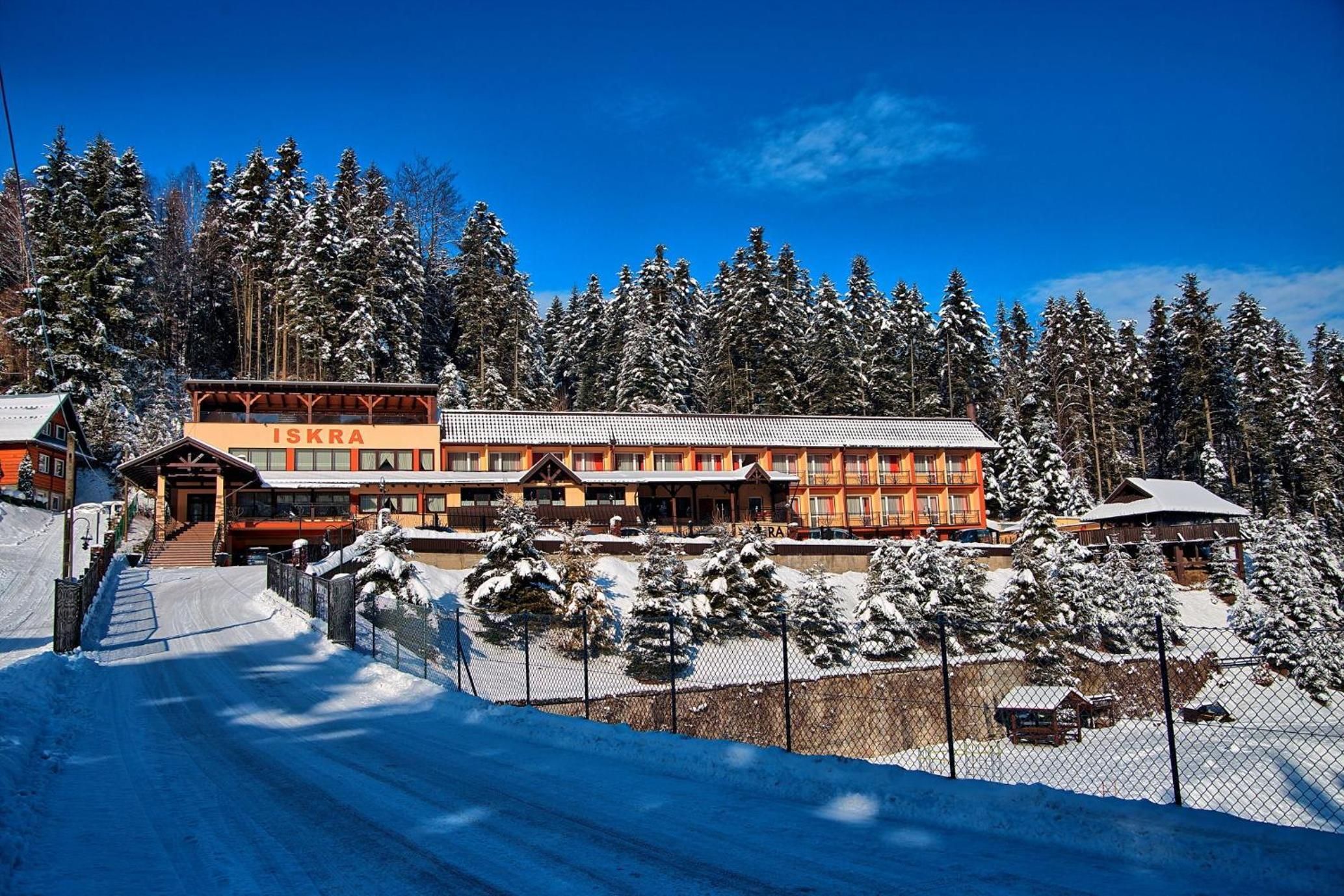 Un centro de esquí con un gran edificio principal, un paseo cubierto y árboles cubiertos de nieve.