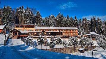 Un centro de esquí con un gran edificio principal, un paseo cubierto y árboles cubiertos de nieve.