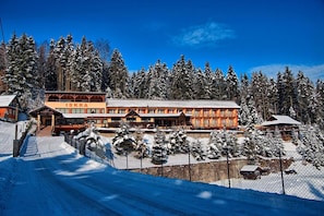 Un centro de esquí con un gran edificio principal, un paseo cubierto y árboles cubiertos de nieve.