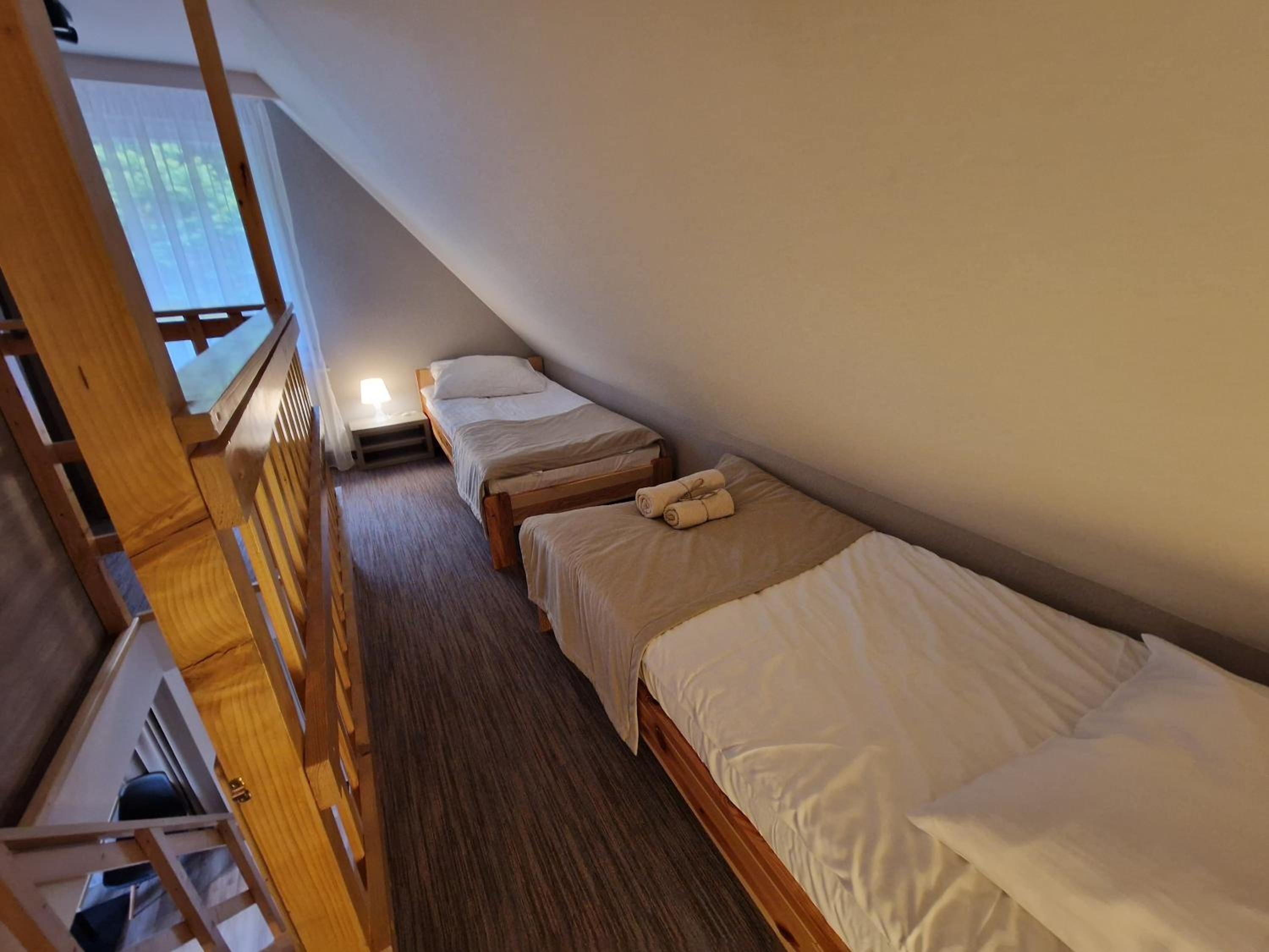 Habitación tipo dormitorio con literas, una escalera de madera y una ventana con persianas.