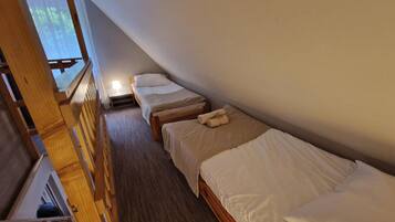 Habitación tipo dormitorio con literas, una escalera de madera y una ventana con persianas.