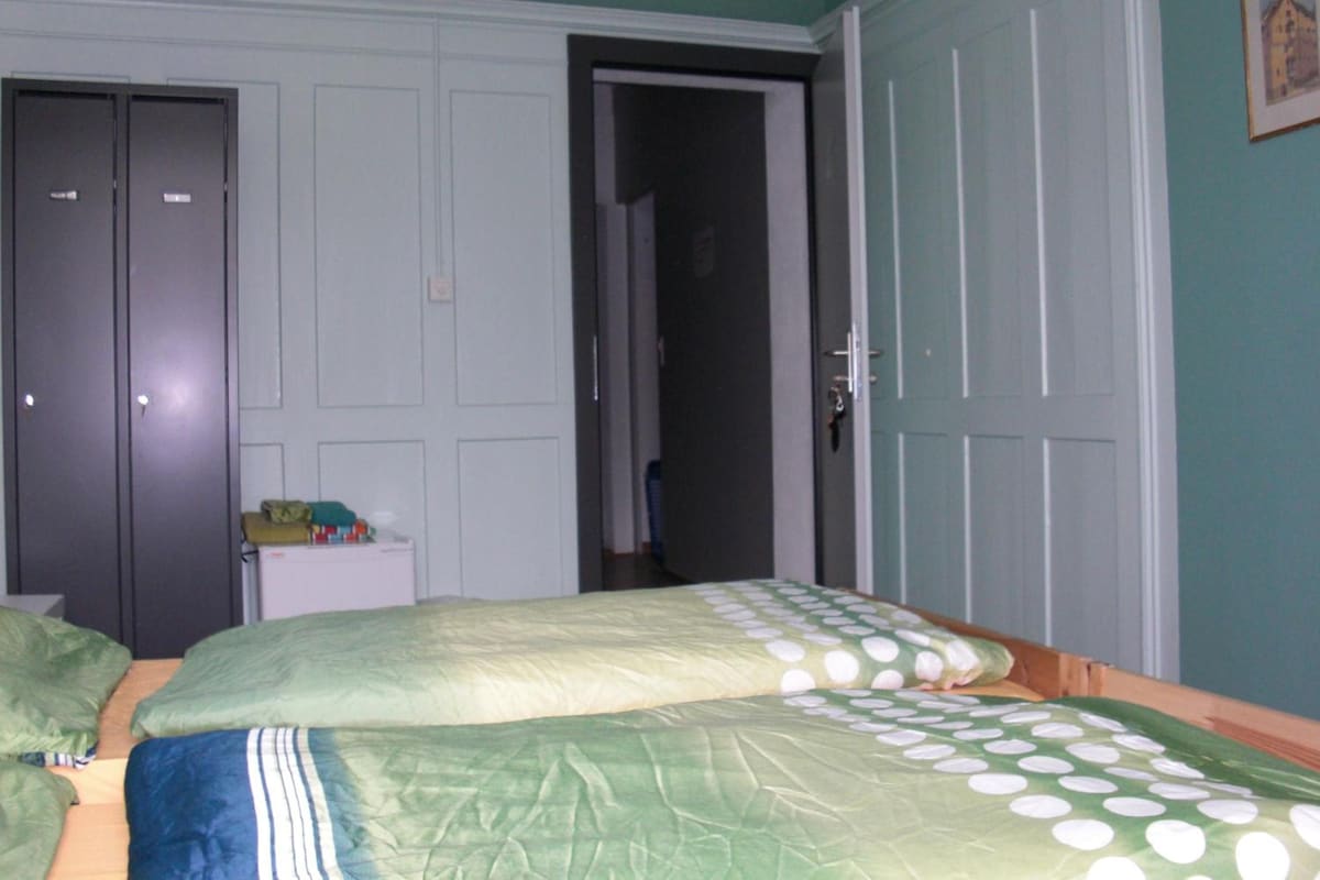 Ein Schlafzimmer mit zwei Betten, einem Kleiderschrank und einer Tür zu einem weiteren Raum.
