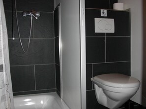 Ein Badezimmer mit Dusche, Toilette und einem Handtrockner.