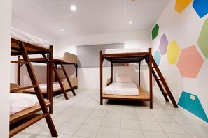 A room with bunk beds, white walls, and a colorful hexagonal wall decoration. - Nacho Hostel Cebu (Talisay)