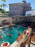 Zona de piscina con gente nadando y relajándose alrededor.