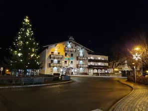 Ein Gebäude mit mehreren Balkonen, einem Weihnachtsbaum und einem Schild mit der Aufschrift 'KALSWIRT'.