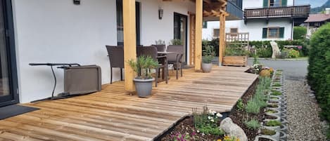 A wooden deck with outdoor furniture, potted plants, and a garden with a stone pathway.