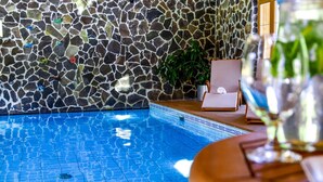Piscina com parede de azulejos em mosaico e um vaso com planta.