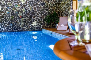 En swimmingpool med væg af mosaikfliser og en potteplante.