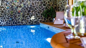 A swimming pool with a mosaic tile wall and a potted plant.