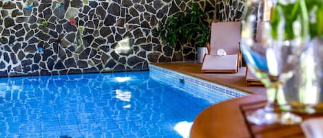 A swimming pool with a mosaic tile wall and a potted plant.