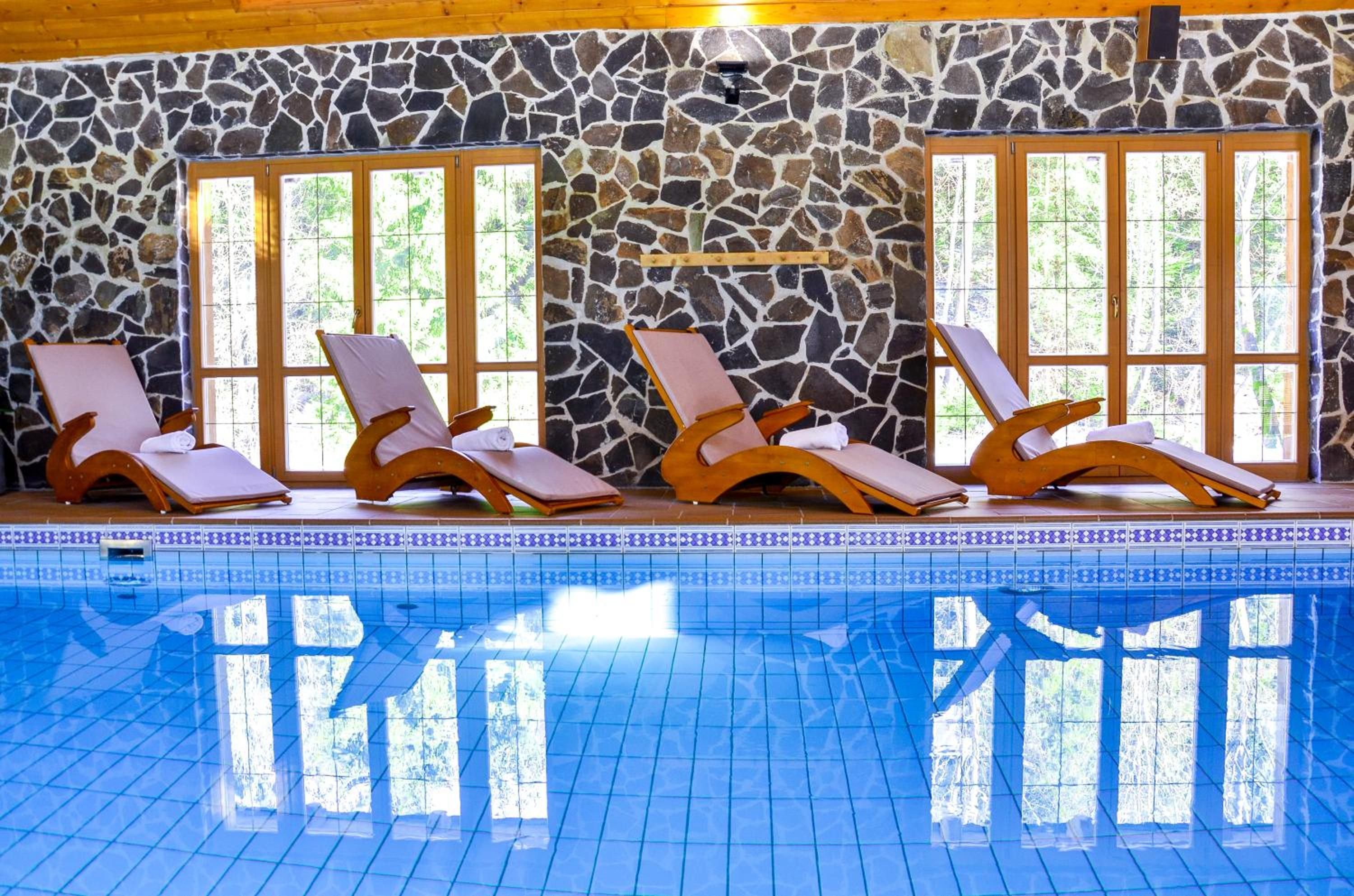 A pool area with four sun loungers and a stone wall.