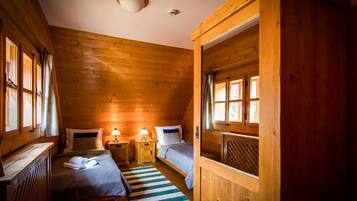 A cozy cabin room with two beds, a wooden ceiling, and a window.