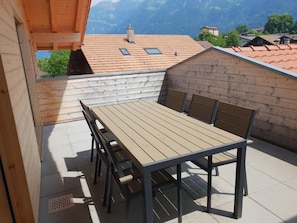 A wooden deck with a table and chairs, overlooking a mountainous landscape. - Swiss Chalet Holidays Ringgenberg (Ringgenberg)