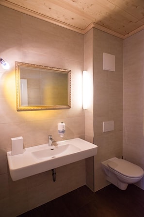 Un bagno con un lavandino bianco, uno specchio con cornice dorata e un water.