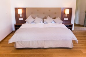 Un letto matrimoniale con copriletto a quadri, due comodini con lampade e una testiera in legno.