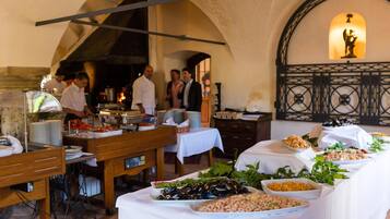 Ein reichhaltiges Buffet mit verschiedenen Speisen und eine Gruppe von Personen in einem Essbereich mit einer Rundbogenzelle.