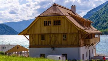Eine Holzhütte mit Balkon, einem kleinen Anbau und Blick auf einen See und Berge.
