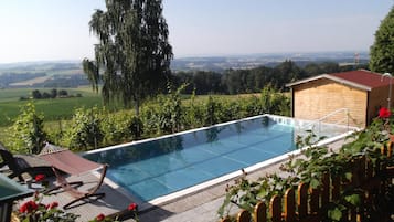 Ein klares, blaues Schwimmbecken mit Blick auf die Landschaft, umgeben von viel Grün und einer Holzkonstruktion.