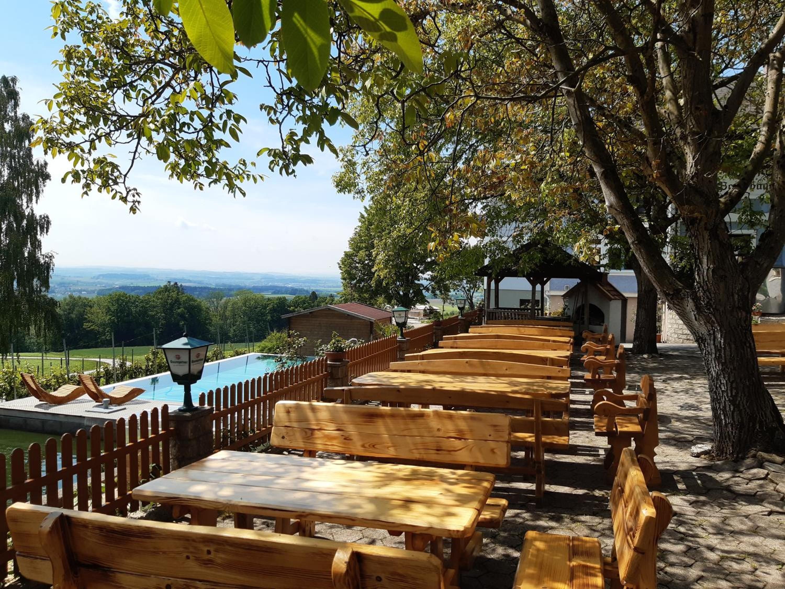 Eine Holzterrasse mit Bänken und Tischen mit Blick auf einen Swimmingpool und eine schöne Aussicht.