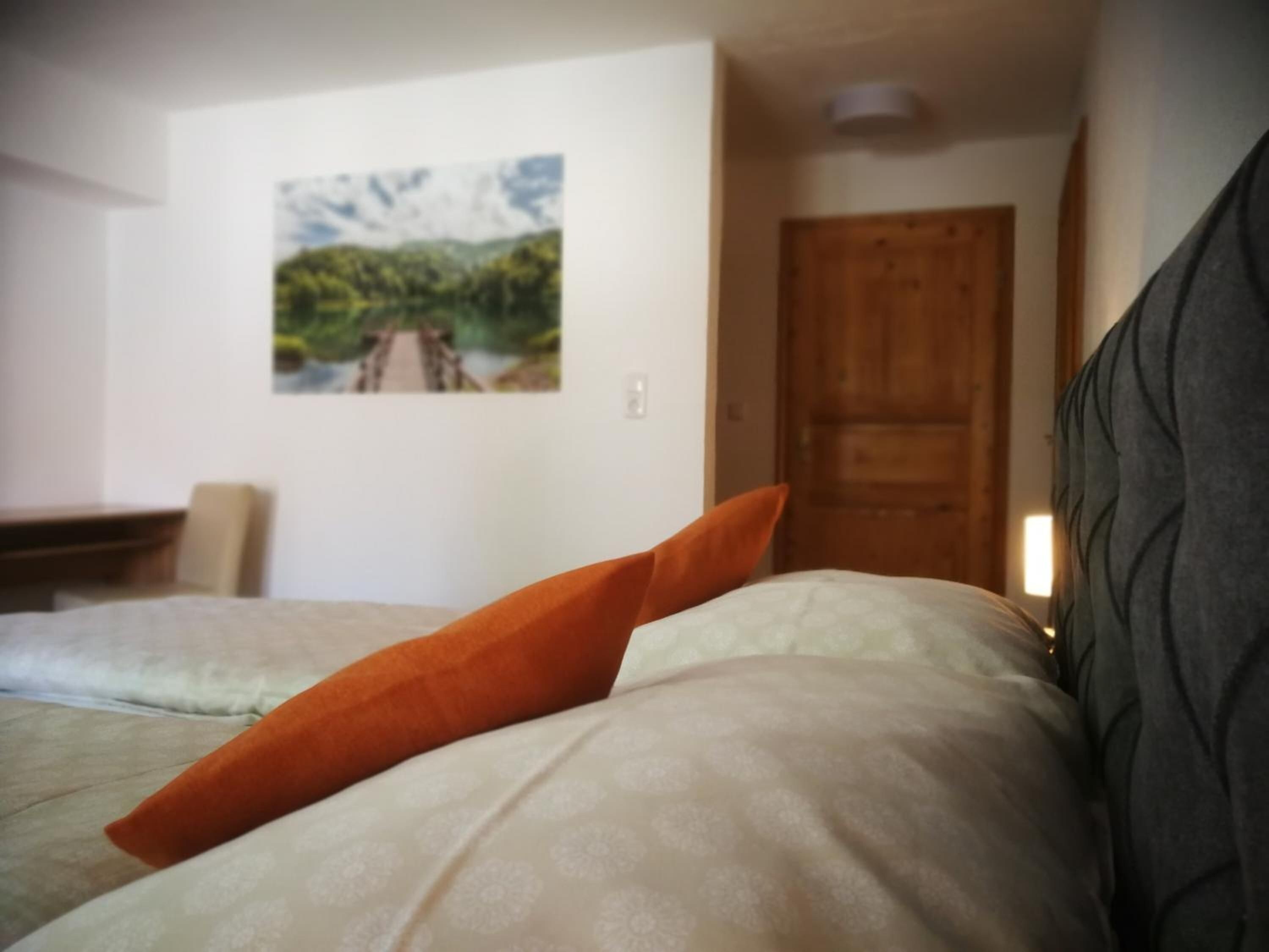 A hotel room with a bed, a painting on the wall, and a wooden door.
