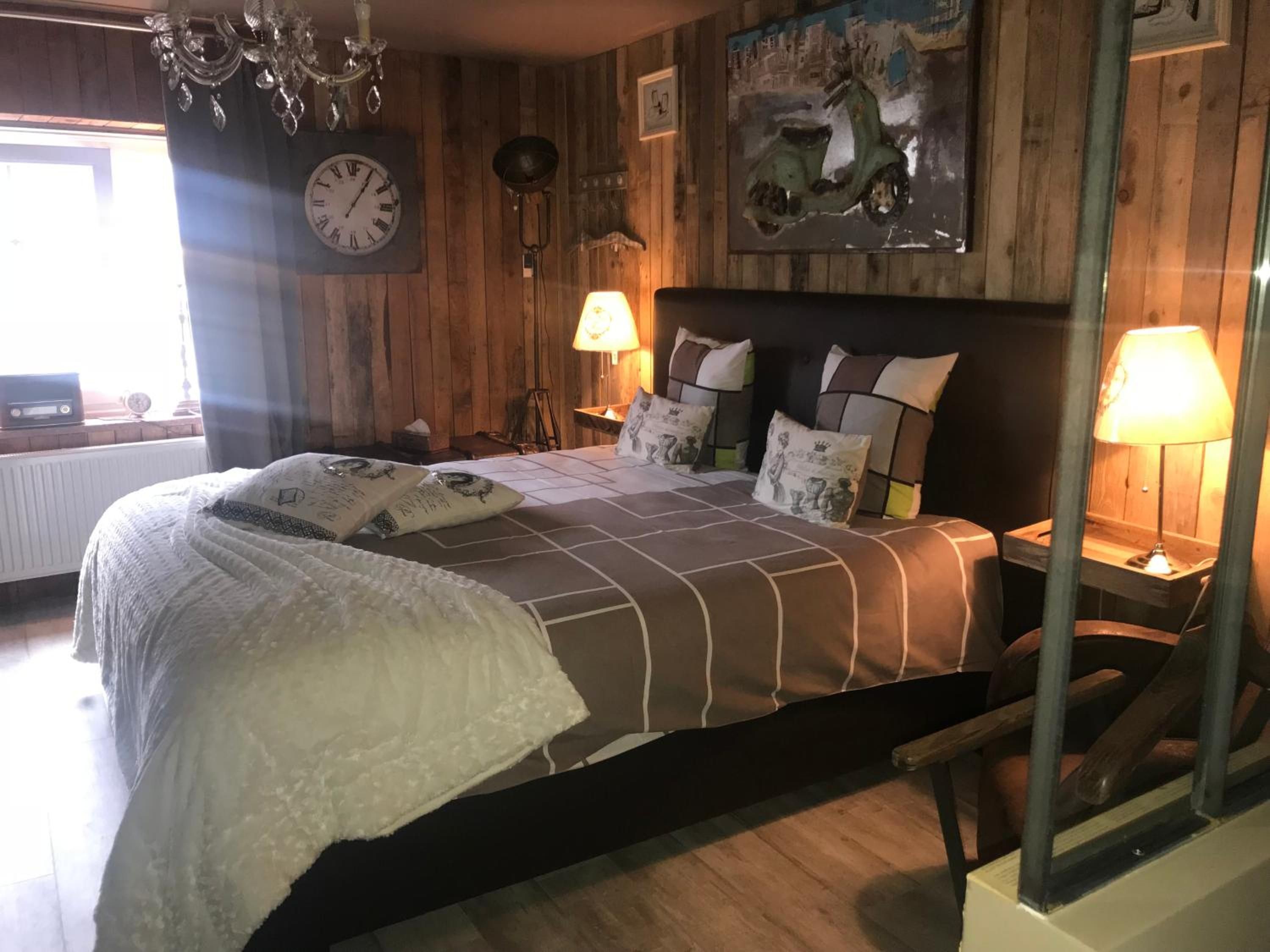 Une chambre à coucher avec un lit, des lampes de chevet, une horloge et un tableau au mur.
