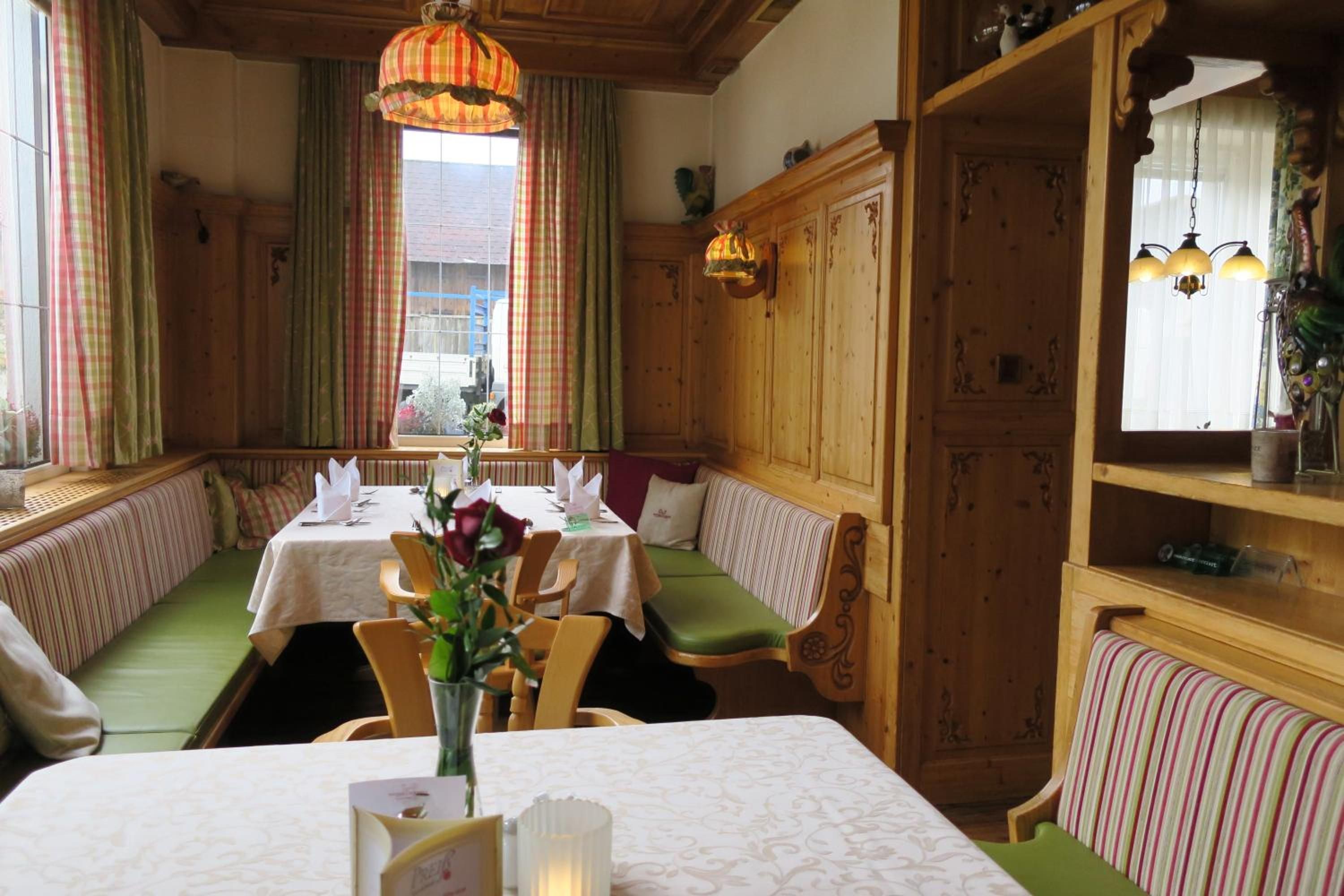 Ein Restaurant mit Sitzboxen, einem Holzkabinett und einem fenster mit Vorhängen.