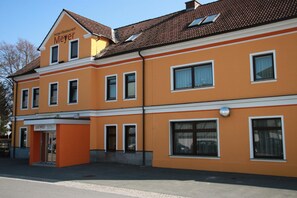 Ett hotell med en gul fasad, många fönster och en skylt som visar att det är ett hotell och en restaurang.