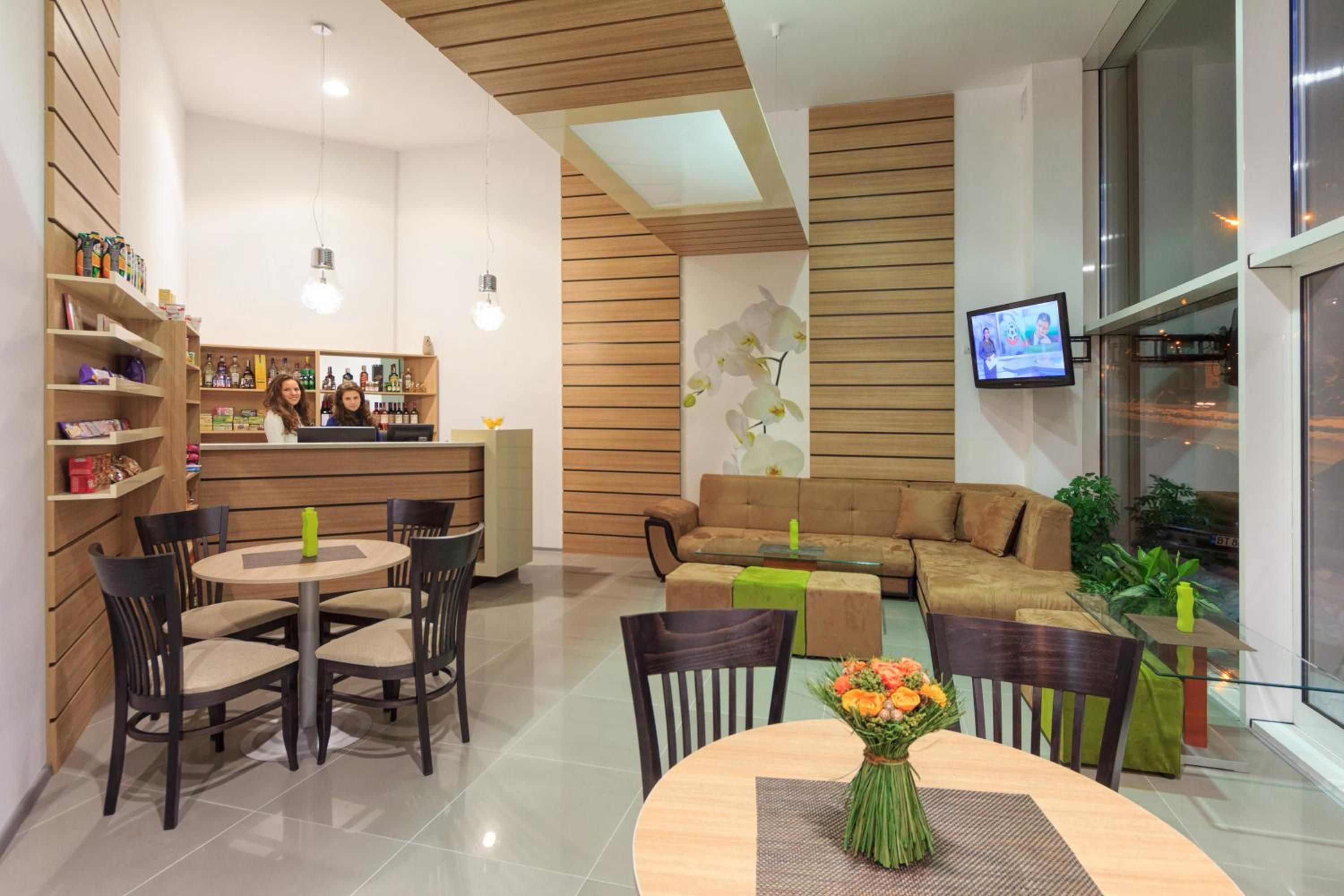 Un área de lounge moderna con bar, asientos y una pantalla de televisión.