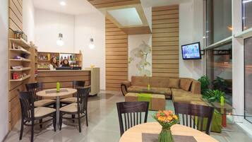 Un área de lounge moderna con bar, asientos y una pantalla de televisión.