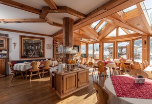 A spacious dining area with wooden furniture and large windows. - Wellnesshaus Reichelt (Radstadt)