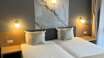 A double bed with two nightstands, a marble wall, and two wall-mounted lamps.