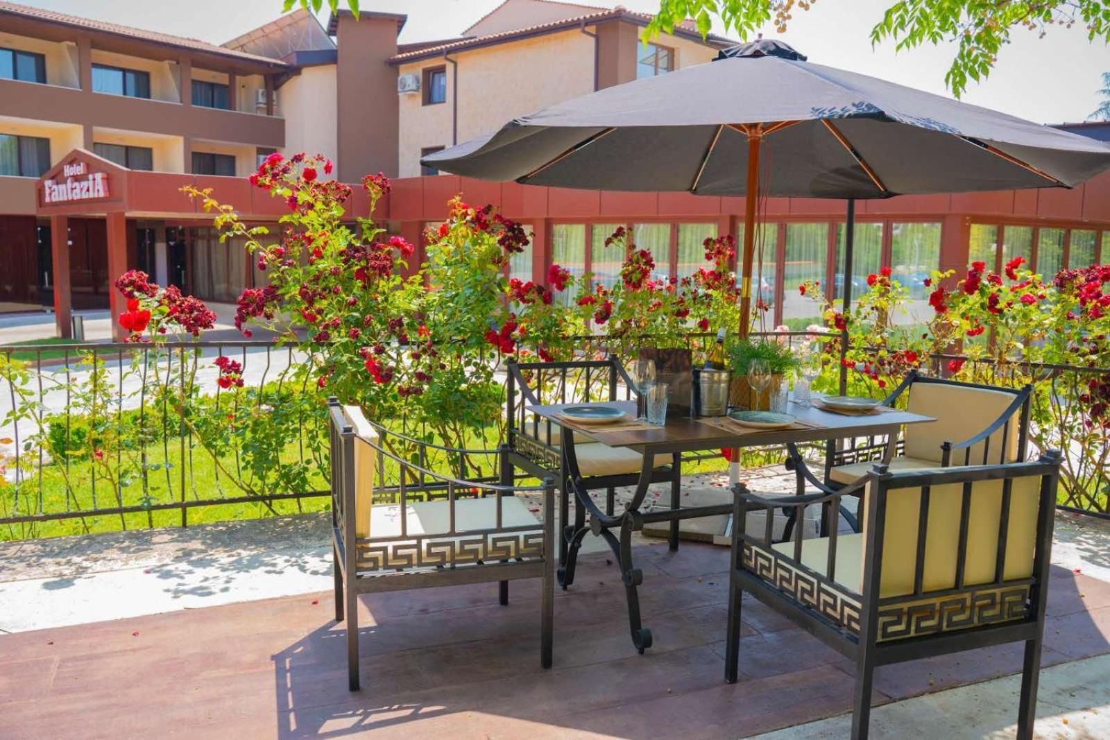 Un patio al aire libre con una mesa y sillas, rodeado por una cerca y un edificio con un letrero que dice 'Hotel Fantasia'.