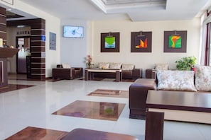 A modern hotel lobby with a reception desk, seating area, and artwork on the walls.