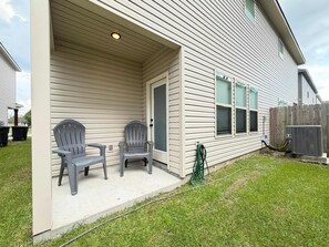 A residential exterior with a covered porch, two chairs, a door, and an air conditioning unit. - Tiger Country Retreat in Baton Rouge - CB1008 (Baton Rouge)
