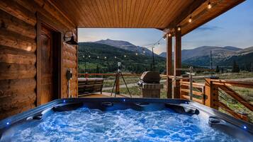 A hot tub with a wooden deck and a view of mountains.