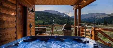 Un jacuzzi con terraza de madera y vista a las montañas.