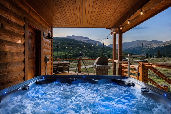 A hot tub with a wooden deck and a view of mountains.