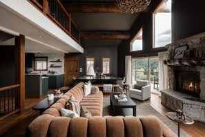 A spacious living area with a large sofa, a fireplace, and a kitchen in the background.