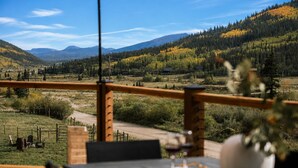 A dining area with a table set for two, overlooking a mountainous landscape with autumn foliage. - Epic Views, Sauna, Dog Lovers 5BR, 25 min to Breck (Breckenridge)
