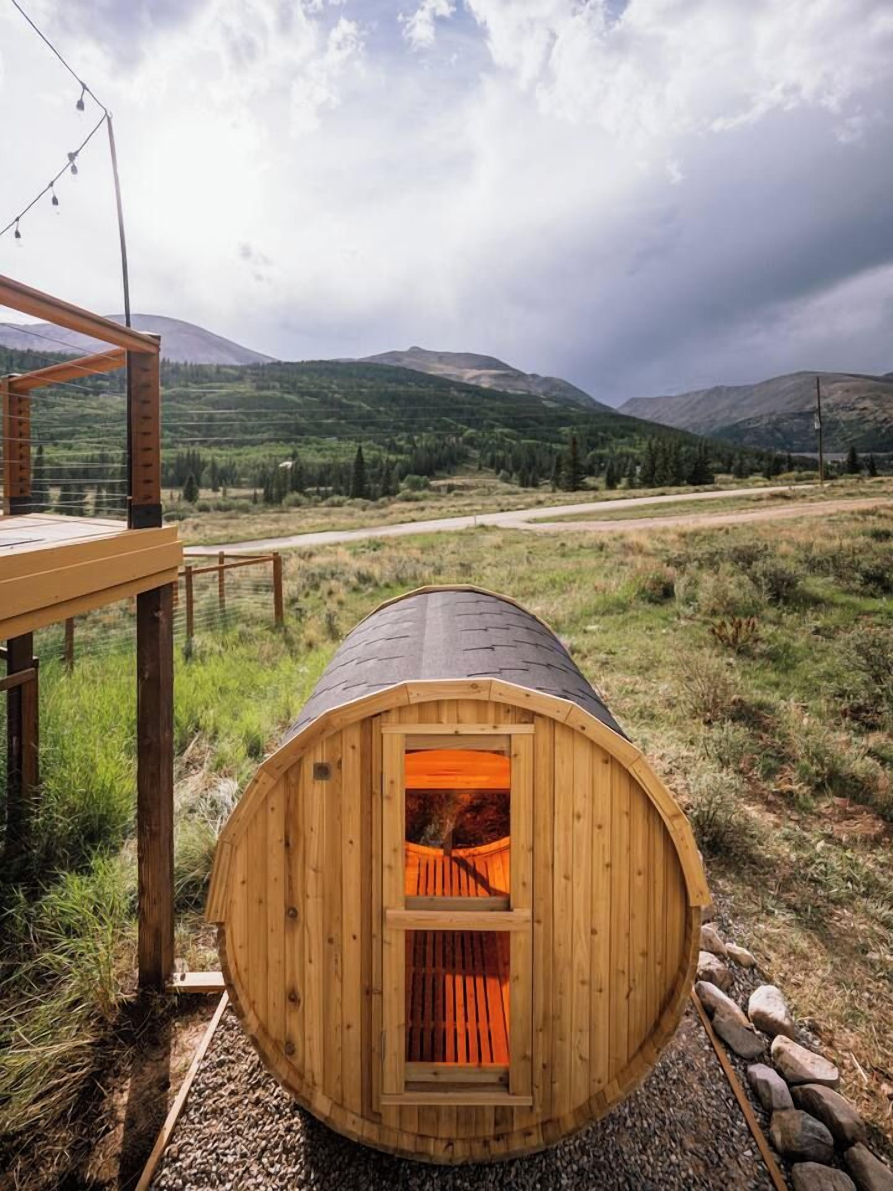Une cabane en bois avec un toit en pente, une terrasse en bois et une vue sur un paysage montagneux.
