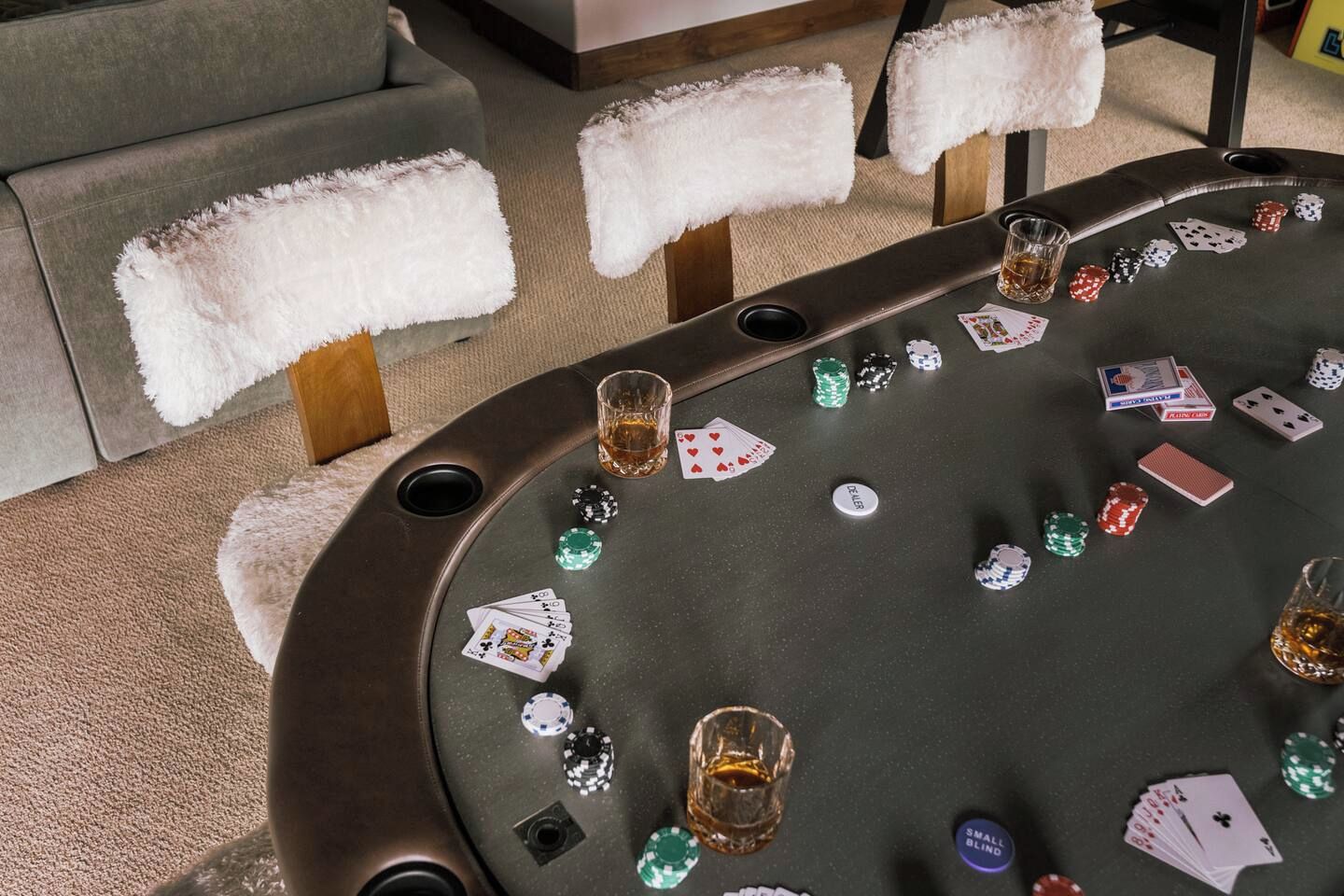 Une table de casino avec des cartes et des jetons, un verre de whisky et un bouton portant l'inscription « SMALL BLIND ».