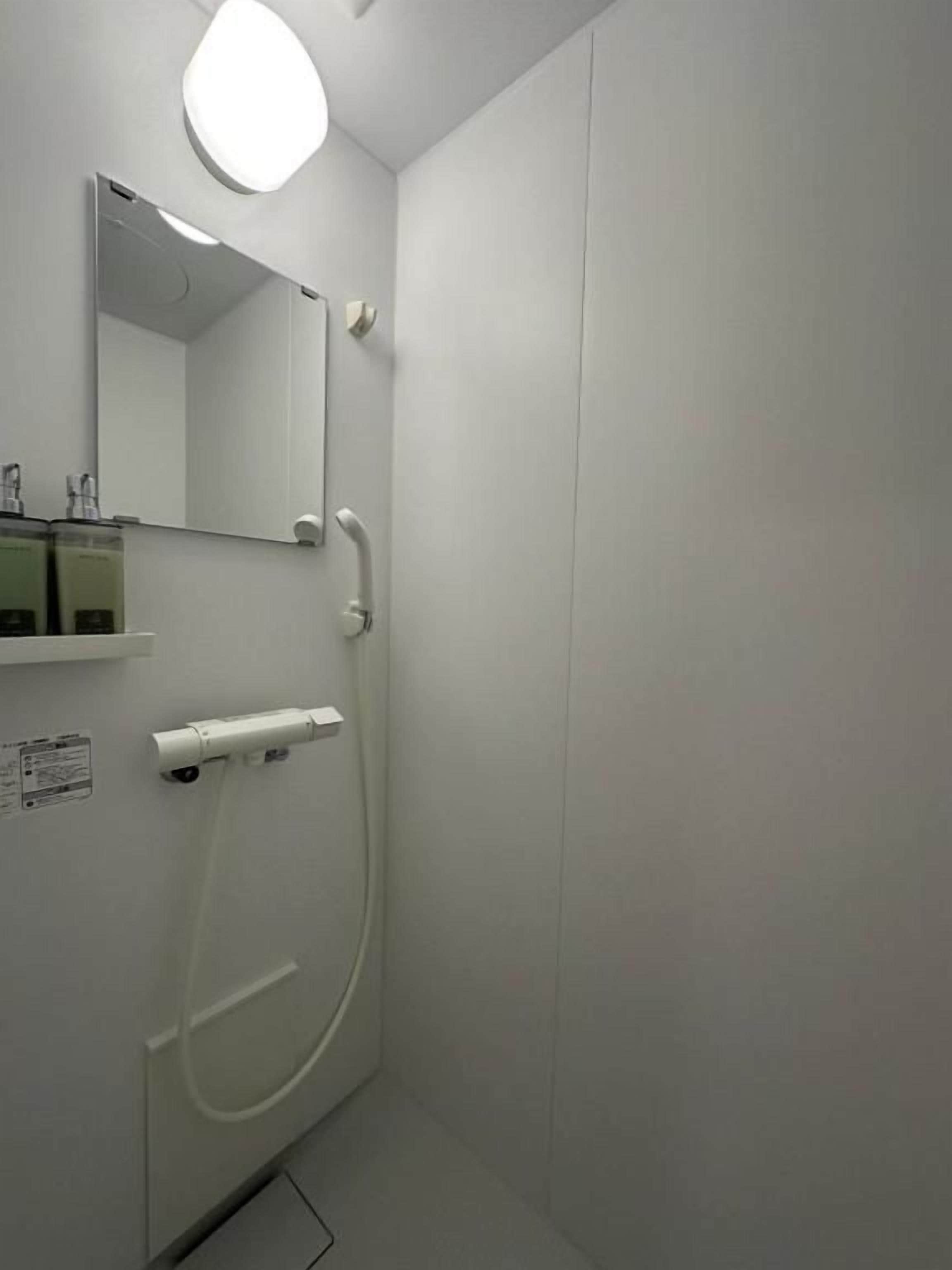 A bathroom with a toilet, a sink, a mirror, and a shower.