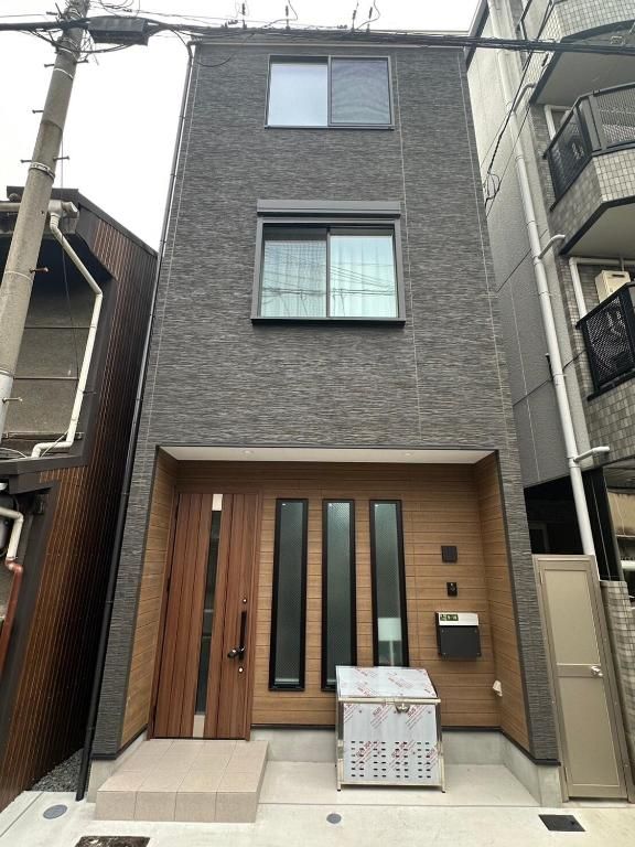 Een modern, twee verdiepingen hoog gebouw met een houten deur, grote ramen en een klein terras.