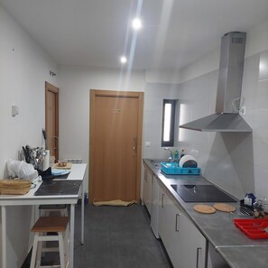 Una cocina compacta con puerta de madera, una ventana, extractor de acero inoxidable y un lavamanos.