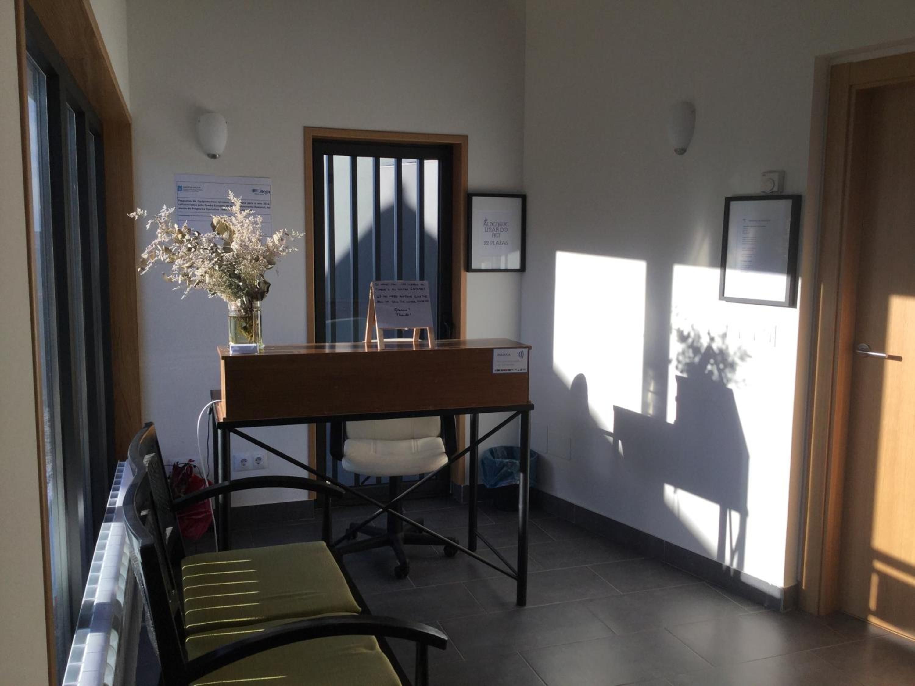 A reception area with a reception desk, a bench, a potted plant, and framed certificates on the wall.