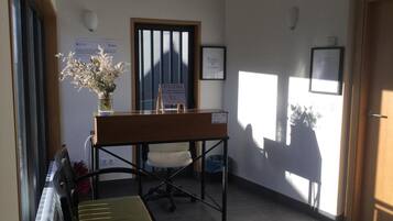 A reception area with a reception desk, a bench, a potted plant, and framed certificates on the wall.