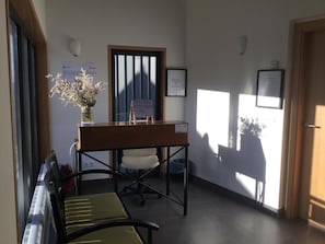 A reception area with a reception desk, a bench, a potted plant, and framed certificates on the wall.